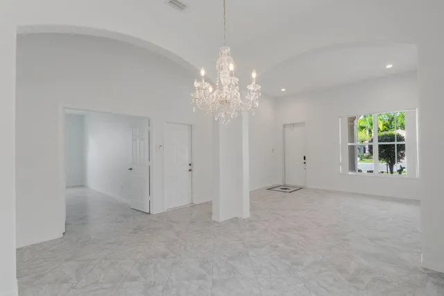 a view of an empty room with window chandelier fan
