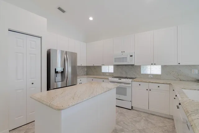 a kitchen with granite countertop white cabinets and stainless steel appliances