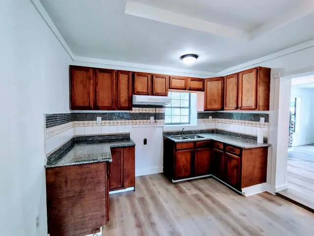 a kitchen with stainless steel appliances granite countertop wooden cabinets a stove top oven a sink and dishwasher