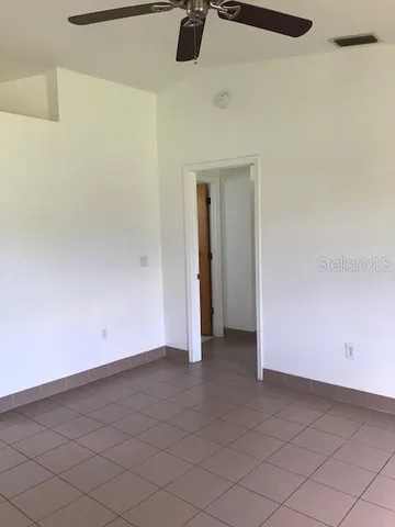 an empty room with a ceiling fan and carpet