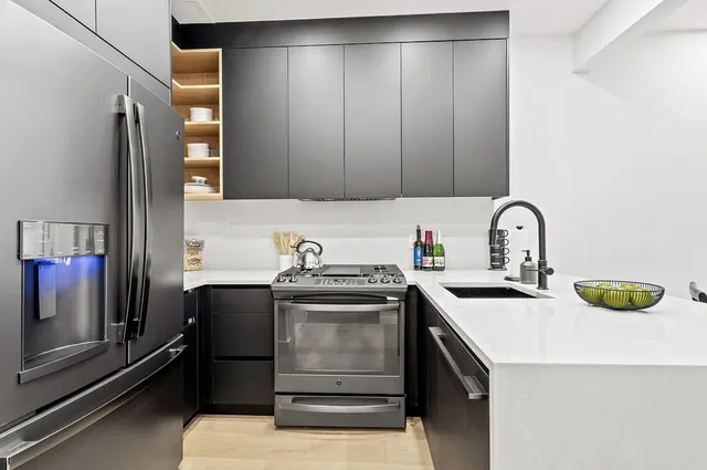 a kitchen with stainless steel appliances granite countertop a sink a refrigerator and wooden cabinets with wooden floor