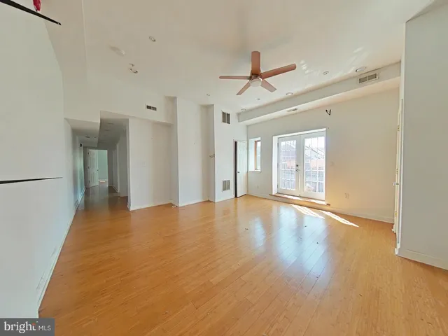 a view of empty room with wooden floor and fan