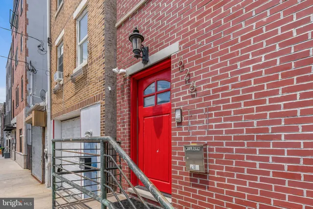 a brick building with a red door and a shower