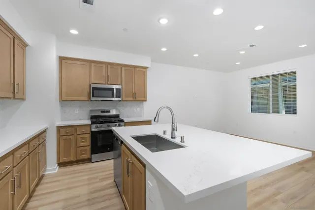 a kitchen with a sink a stove top oven and wooden floor