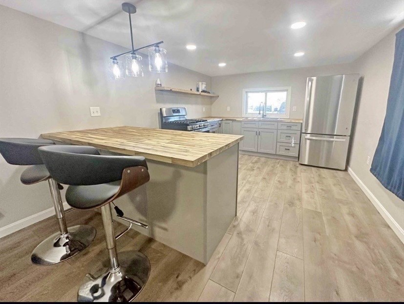 a view of a kitchen with kitchen island granite countertop wooden floor and a refrigerator