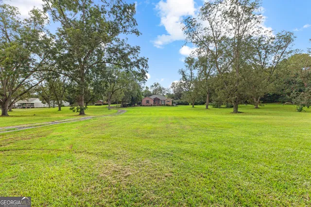 a view of a house with a big yard and large trees