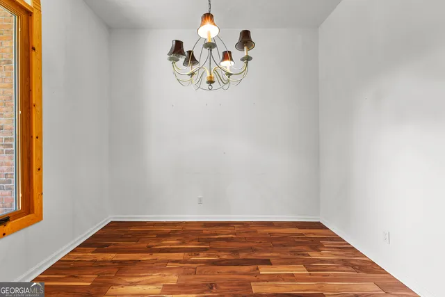 a view of a room with wooden floor a ceiling fan and windows
