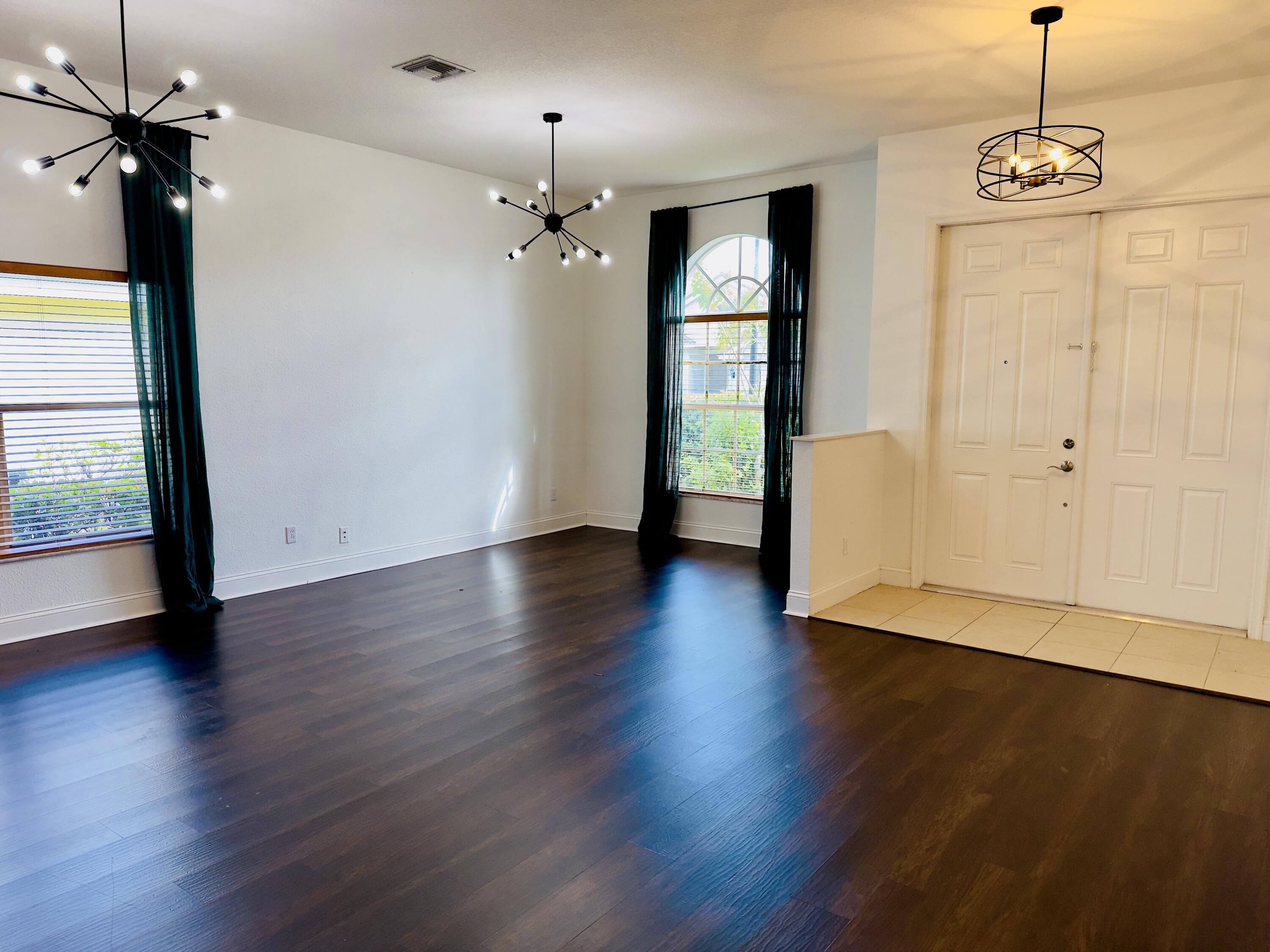11479 Southwest Glengarry Court Port St. Lucie, FL 34987 - Photo 4 of 24 an empty room with wooden floor chandelier and windows