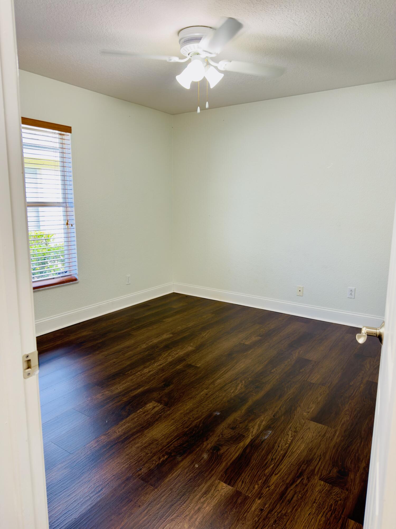 11479 Southwest Glengarry Court Port St. Lucie, FL 34987 - Photo 7 of 24 an empty room with wooden floor chandelier fan and windows
