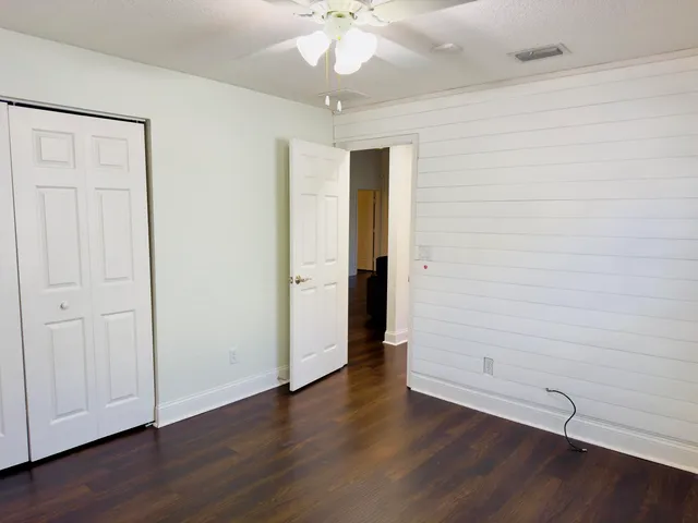 an empty room with wooden floor and a ceiling fan