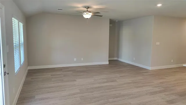 an empty room with a chandelier fan and windows
