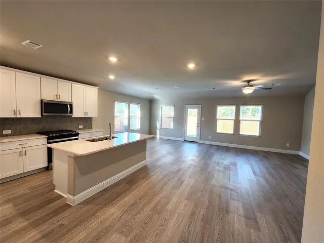 a kitchen with stainless steel appliances a sink a stove a microwave a refrigerator a counter space and cabinets