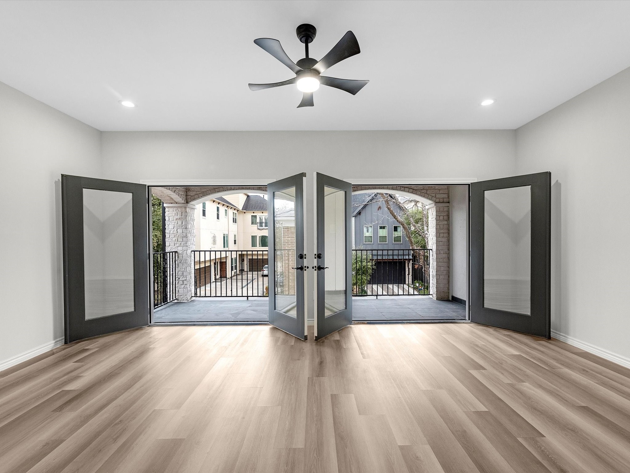 1319 West Bell Street Houston, TX 77019 - Photo 41 of 50 Open game room with light vinyl flooring, featuring double doors leading to an expansive terrace. Ceiling fan and recessed lighting enhance the modern feel, offering a view of neighboring homes.