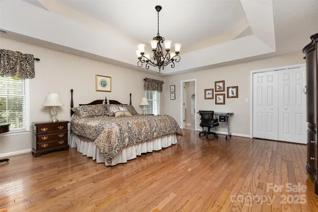 a bedroom with a bed chandelier and a window