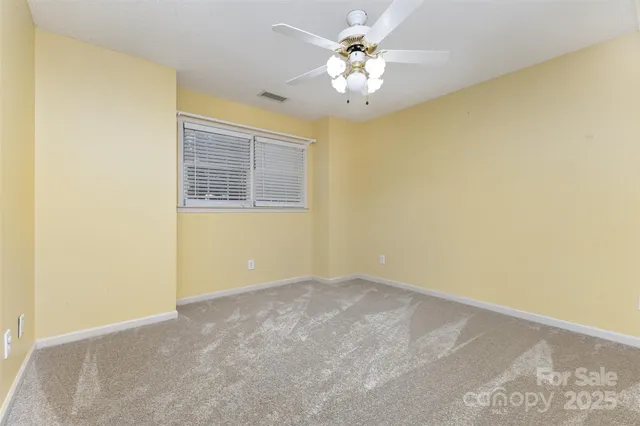an empty room with a chandelier fan and a window