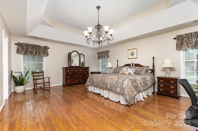 a spacious bedroom with a bed a chandelier and a couch