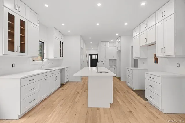 a large white kitchen with kitchen island a sink stainless steel appliances and cabinets