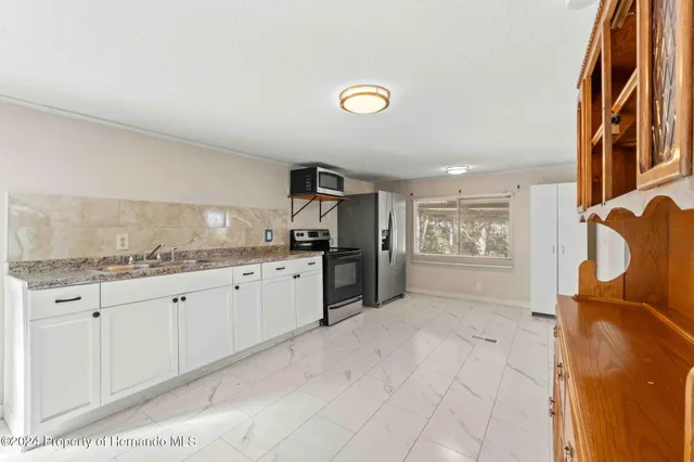 a kitchen with granite countertop a sink and a stove top oven