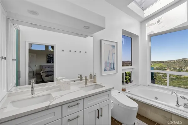 a bathroom with a granite countertop double vanity sink a large mirror a bathtub and next to a window