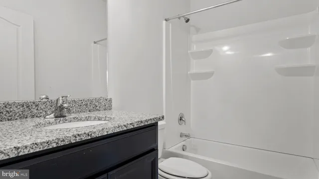 a bathroom with a granite countertop sink a toilet and shower