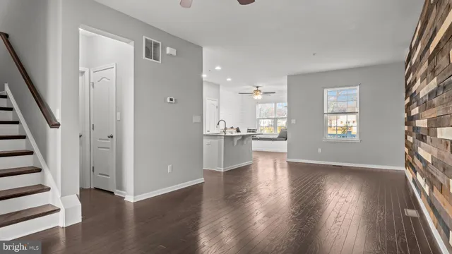 a view of an empty room with wooden floor and a kitchen