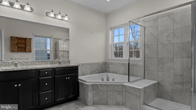 a bathroom with a granite countertop bathtub sink vanity and mirror