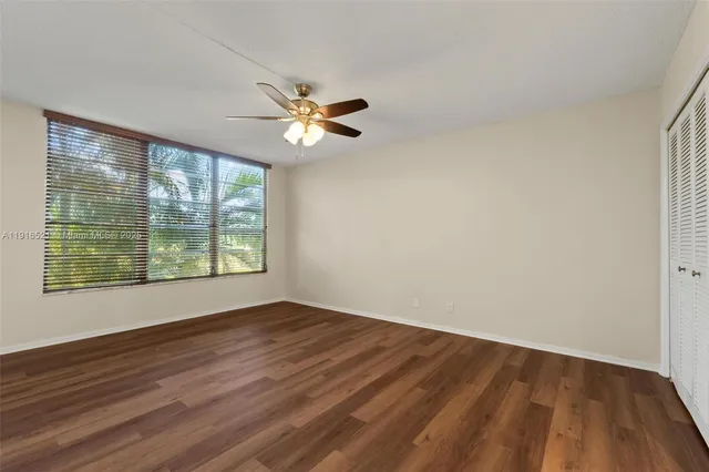 a view of empty room with wooden floor and fan