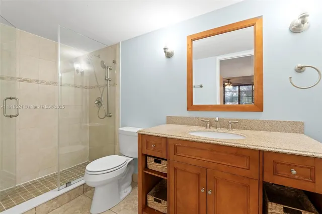 a bathroom with a granite countertop sink toilet a mirror and shower