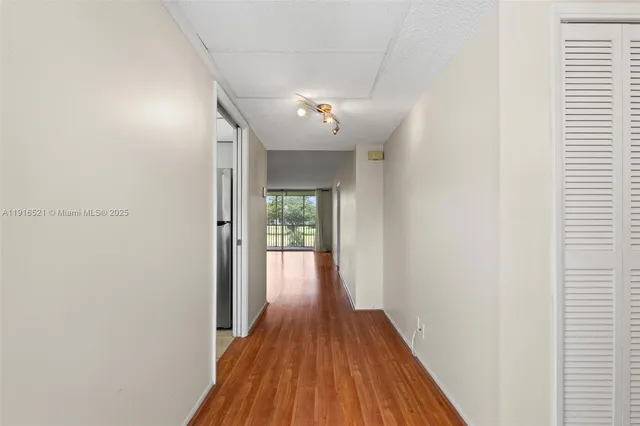a view of a hallway with wooden floor and a ceiling fan
