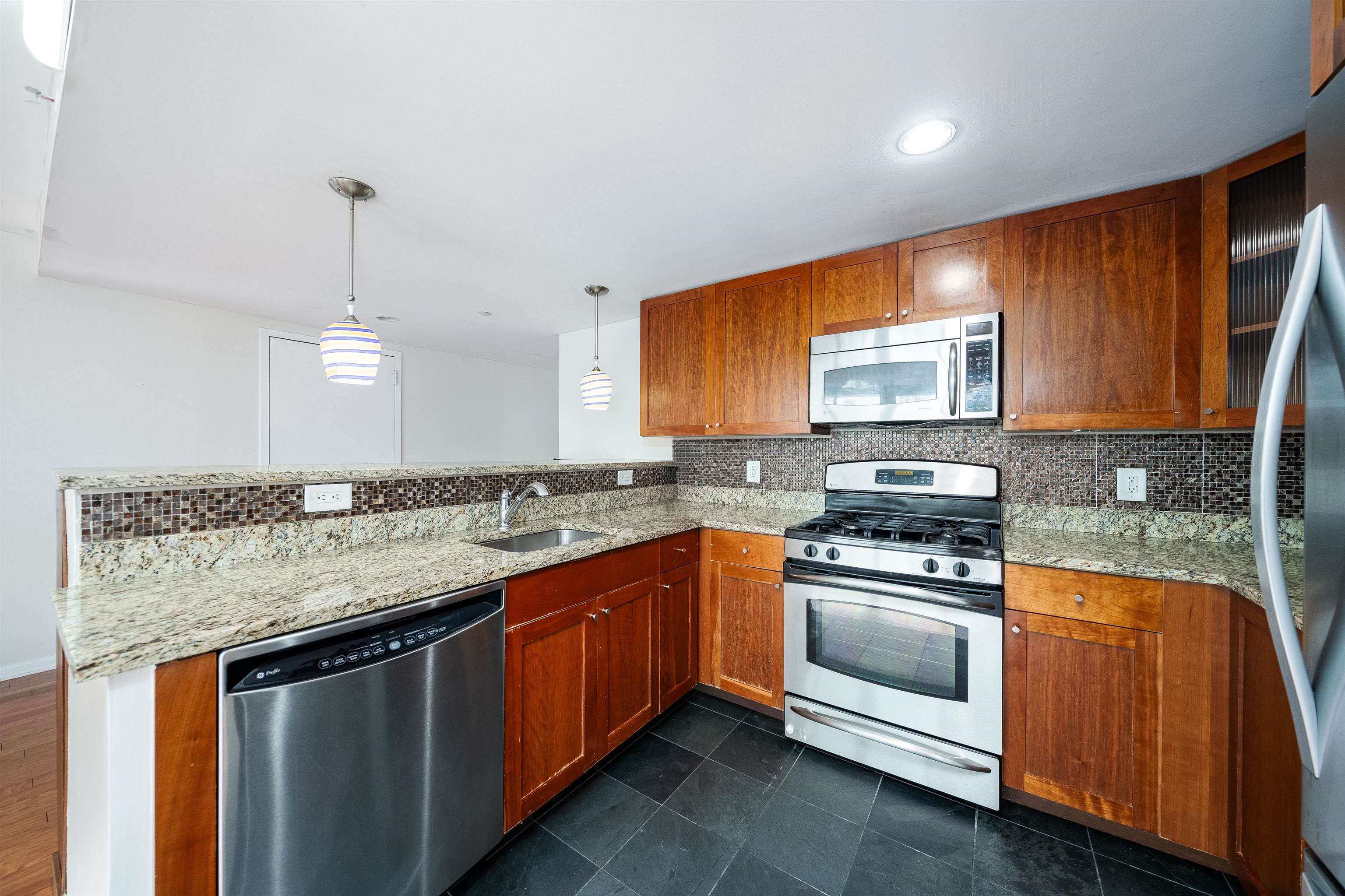 a kitchen with stainless steel appliances granite countertop a sink stove and microwave