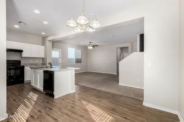 a large kitchen with kitchen island a stove a sink dishwasher a refrigerator and white cabinets with wooden floor