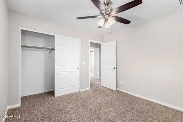 an empty room with closet and a ceiling fan