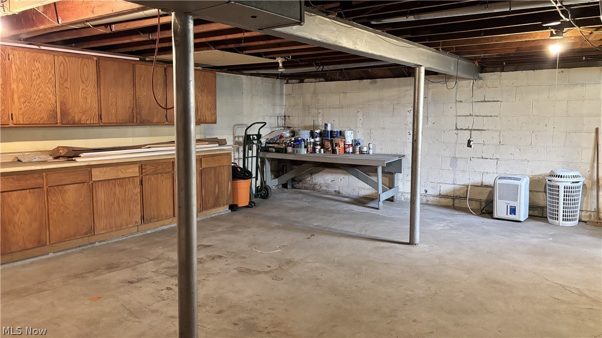 11784 Chamberlain Road Mantua, OH 44255 - Photo 27 of 50 Concrete flooring, exposed ceiling joists, wood-finish cabinetry, and concrete block walls