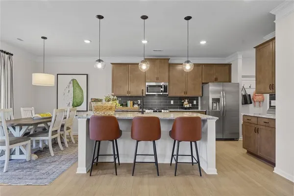 a kitchen with stainless steel appliances granite countertop a stove a refrigerator a kitchen island a dining table and chairs