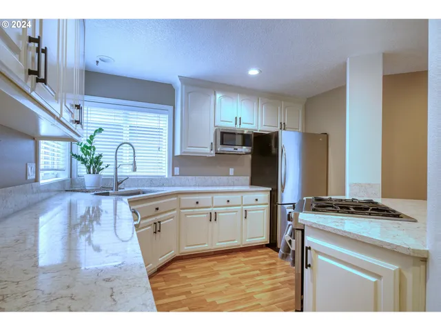 a kitchen with granite countertop a stove a sink dishwasher a refrigerator and a oven with wooden floor