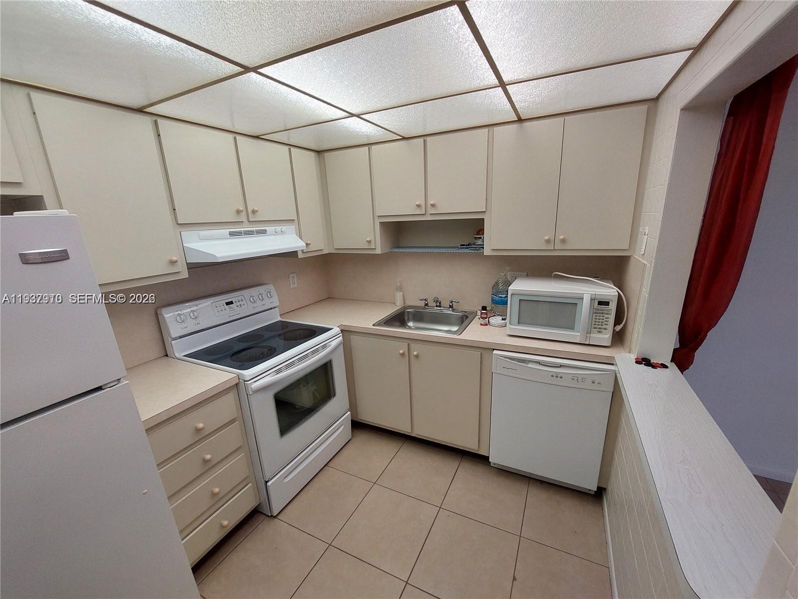 253 South Cypress Road, Unit 206 Pompano Beach, FL 33060 - Photo 7 of 30 a kitchen with white cabinets and white appliances