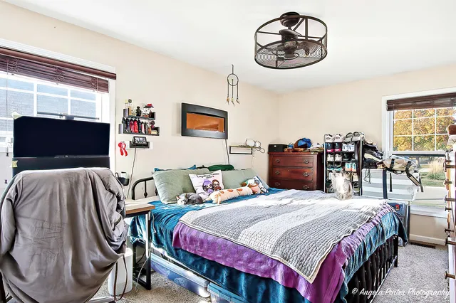a bedroom with a bed and dresser with view of living room