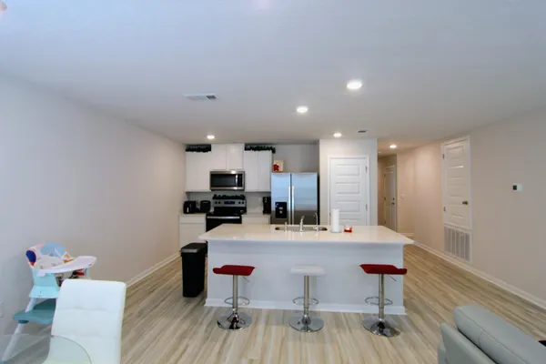 a room with a table chairs wooden floor and a view of kitchen