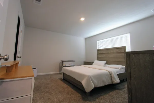 a bedroom with a bed and a flat tv screen on dresser