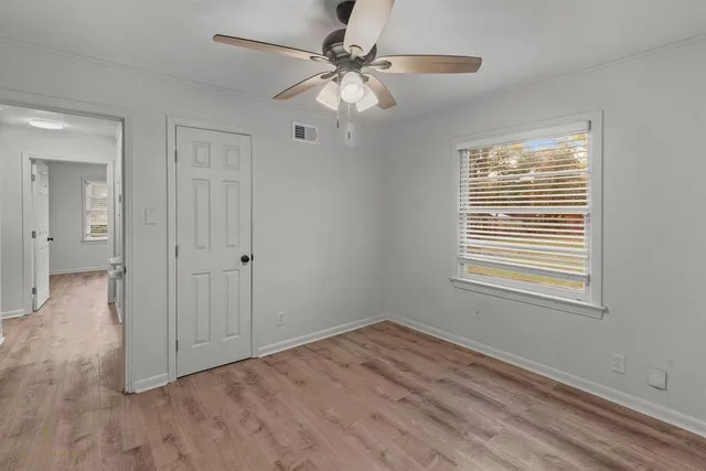 a view of an empty room with a window and a ceiling fan