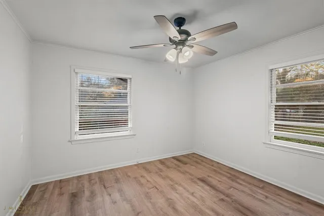 a view of an empty room with wooden floor and a window