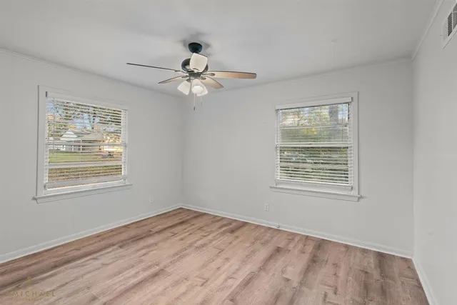 a view of an empty room with a window and wooden floor