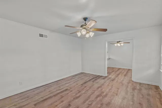 a view of an empty room with chandelier fan