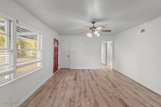 a view of an empty room with a window and wooden floor