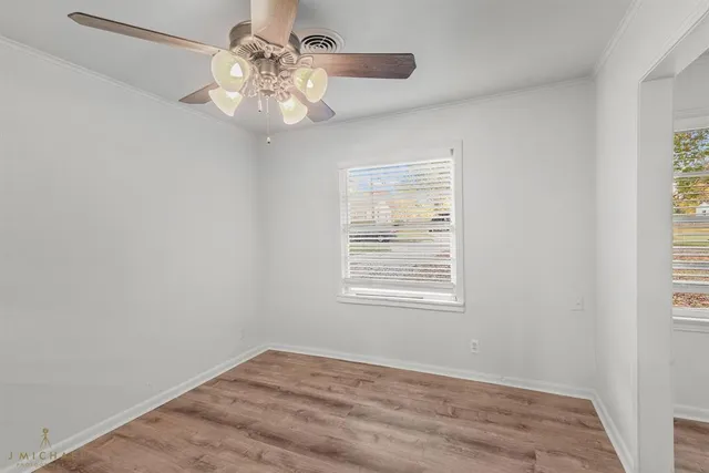 an empty room with a chandelier fan and windows