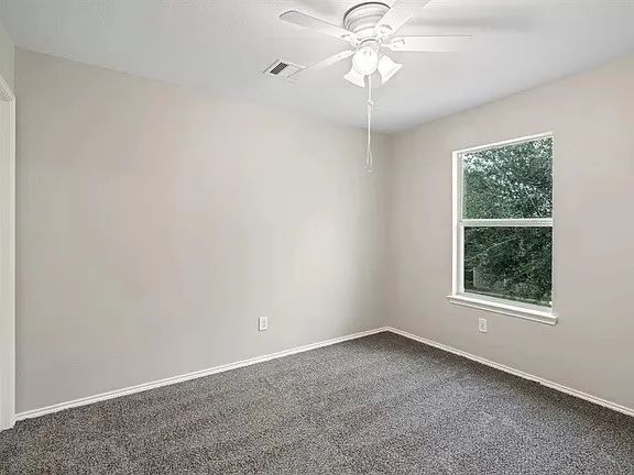 an empty room with a window and a fan