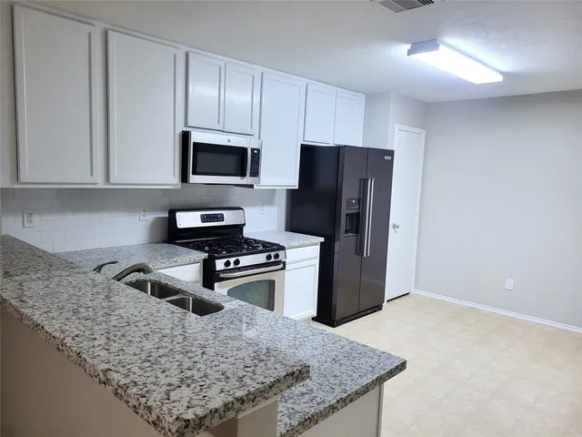 a kitchen with granite countertop a refrigerator stove and microwave