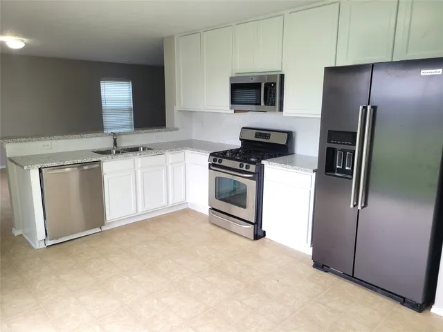 a kitchen with stainless steel appliances granite countertop a refrigerator a stove and a sink