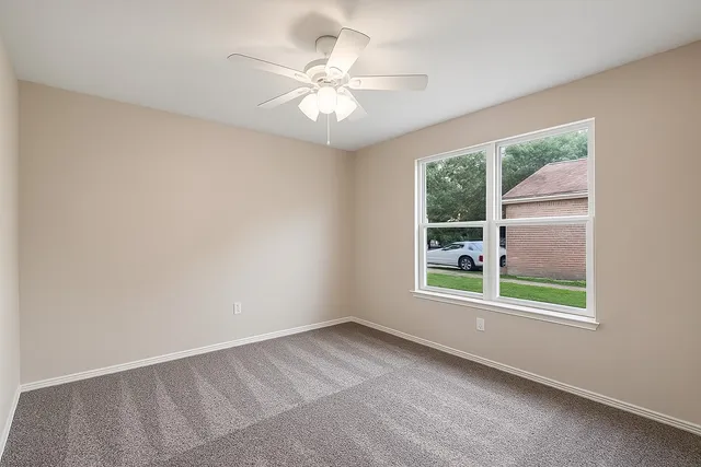 an empty room with windows and chandelier fan