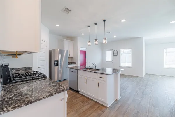 a kitchen with stainless steel appliances kitchen island granite countertop a sink stove and refrigerator